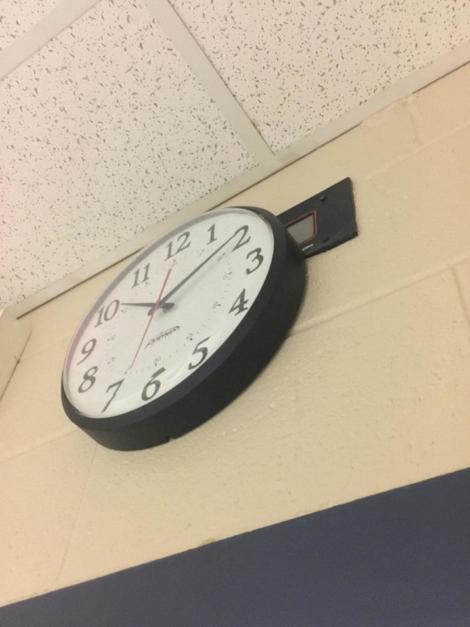 An analog clock rests over its digital predecessor. Long deceased due to a lack of educational funding.