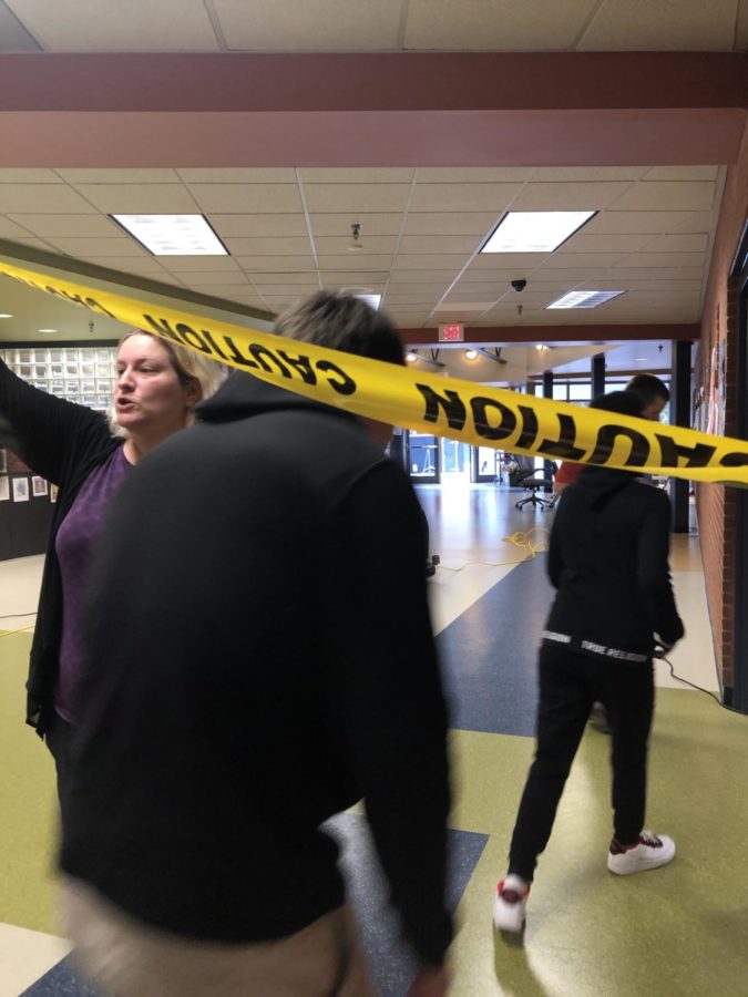 Students are allowed past police tape in order to collect their belongings from the neighboring room, supervised by Ms. Bahl-Moore.