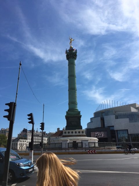 The monument to the Bastille stands tall in the busy square.