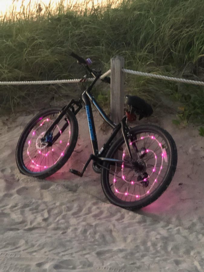 This colorful bike laid on the beach as the sun set. The owner went to go swim in the ocean to take a break from his long ride.