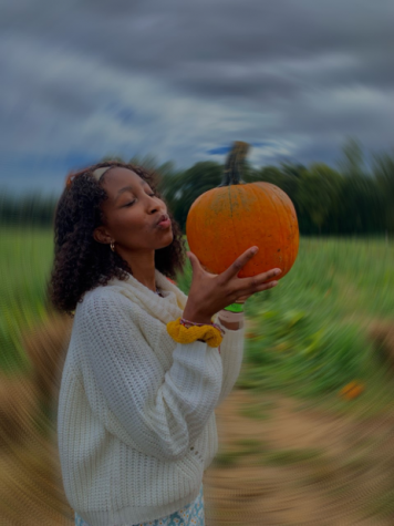 Acting like she enjoyed being outside in the rain pumpkin-picking, Michaiah Berenji poses next to her new baby for the season
