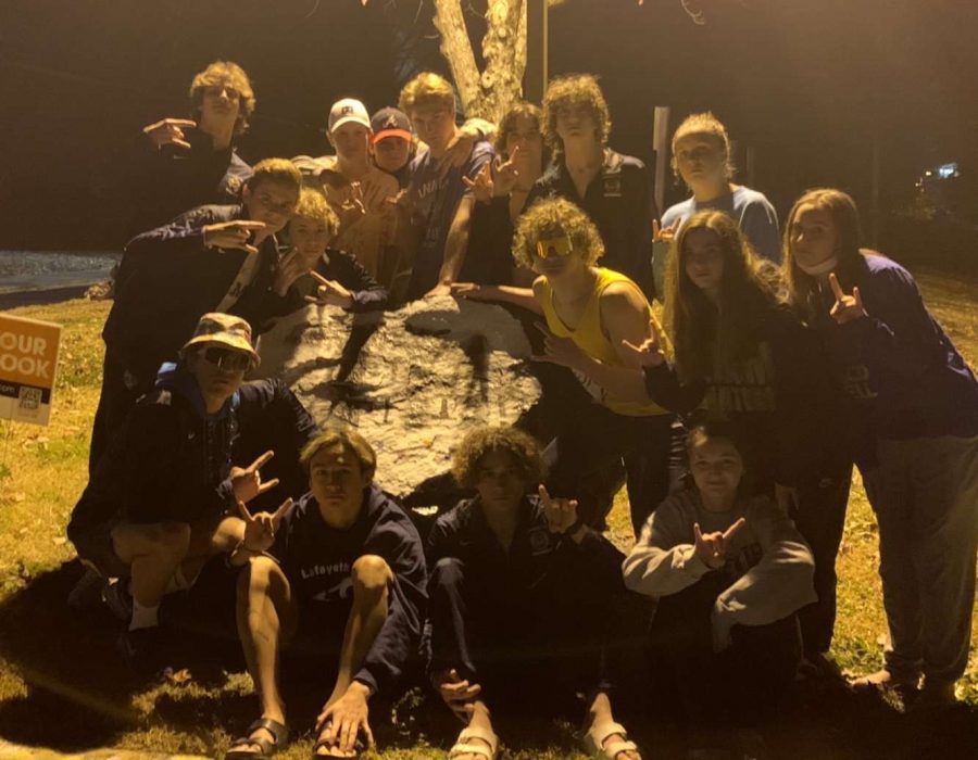 A rival team tried to tag the Lafayette school rock, but failed miserably. The swimmers pose in front of the rock after winning the whole meet.