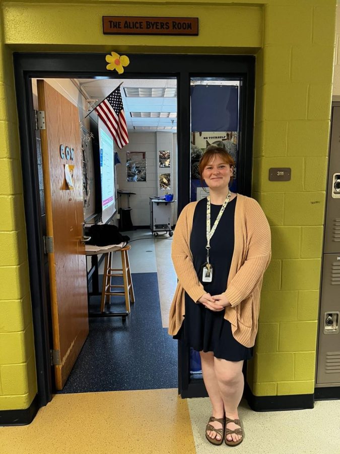 Ms. Cox standing in front of her classroom door ready to get to teaching.