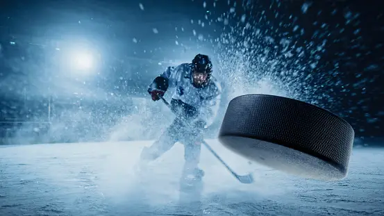Ice Hockey Rink Arena: Professional Player Shooting the Puck with Hockey Stick. IStock.com