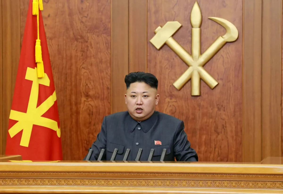 North Korean president Kim Jung Un sitting at the head seat in a government building.