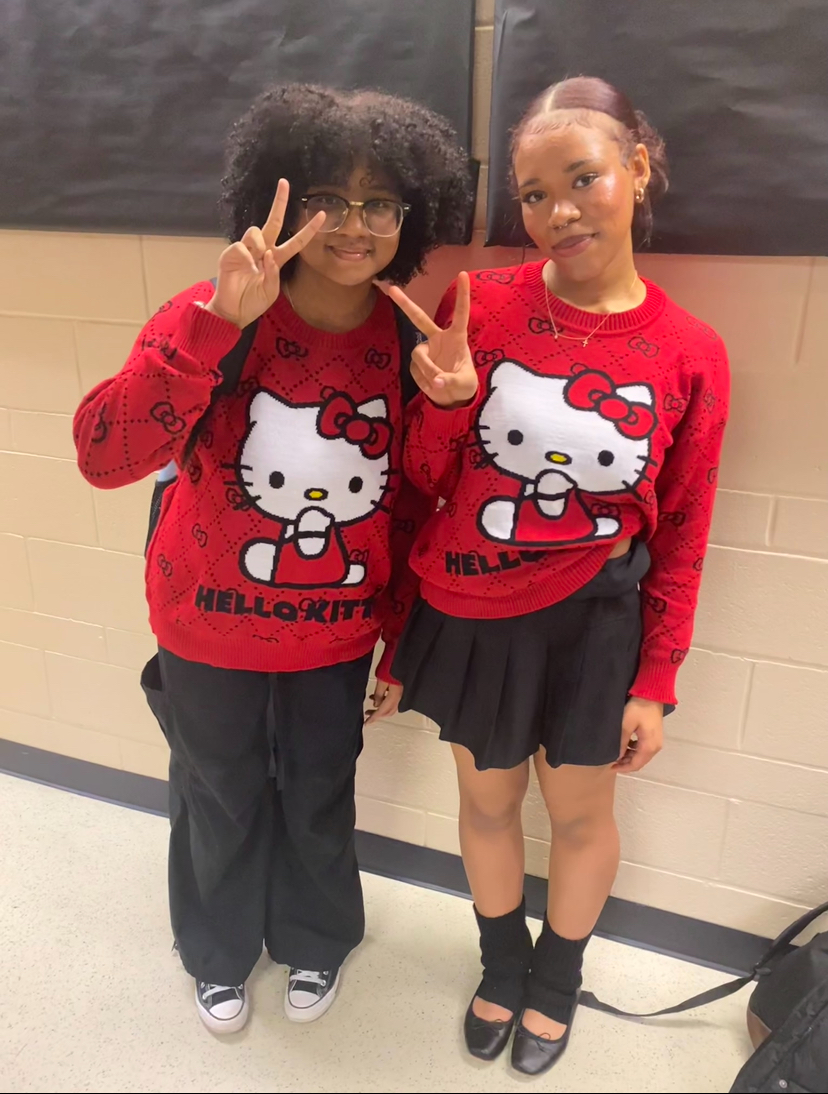 Maaliyah Outz (Left) and Aniya Everett (Right) smile, raising the signature peace sign as they dress up for twin day during the winter break spirit week. 