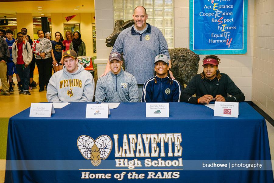 Coach Linn smiles proudly as his players sign on National Signing Day