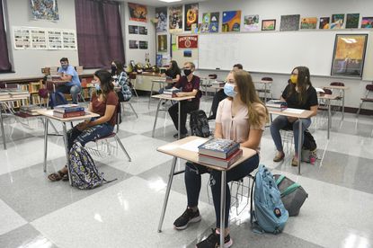 Students sit in class wearing their masks and with their desks spaced away from eachother. 