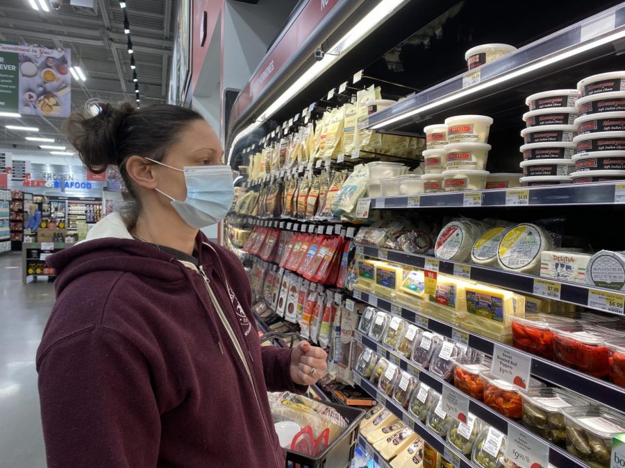 Outside of Earth Fare, a well established grocery store, there's a sign saying all customers and employees must enter the building with a mask or some sort of facial covering. Here my mom and I are looking at different cheeses to buy. Around us, everyone was wearing a mask.