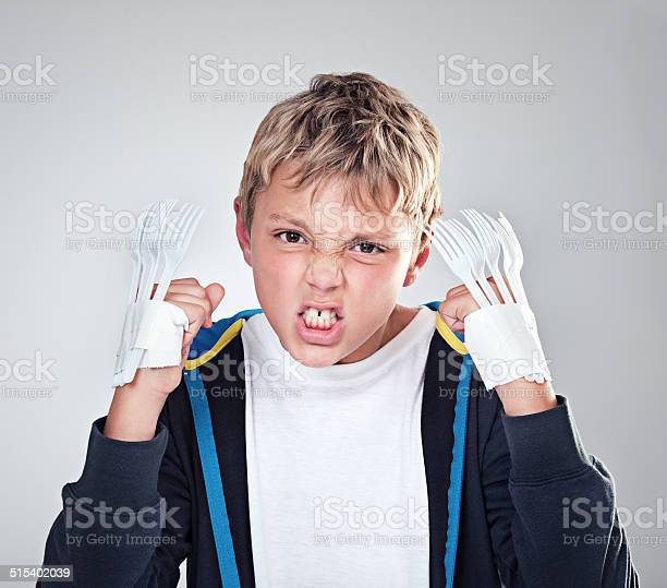 A little boy frowning while showing hands taped to look like claws with forks