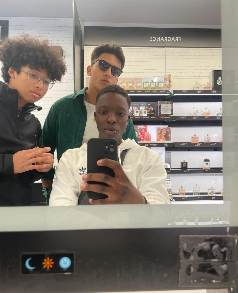 Kai Gokita (Far Left), Emmanuel Anyonje (Middle), taking a photo in a fragrance departments mirror, looking rather dashing.