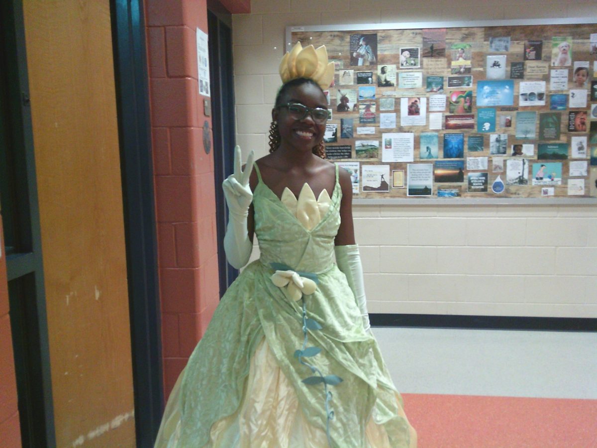 This photo shows a smiling student dressed up at Tiana from the Disney movie the princess and the frog. She said that she loves character day!