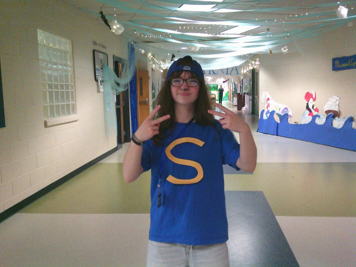 Elissa Neenan is dressed up as Simon from Alvin and the Chipmunks. In this picture she is standing in the junior homecoming hallway, showing her school spirit.