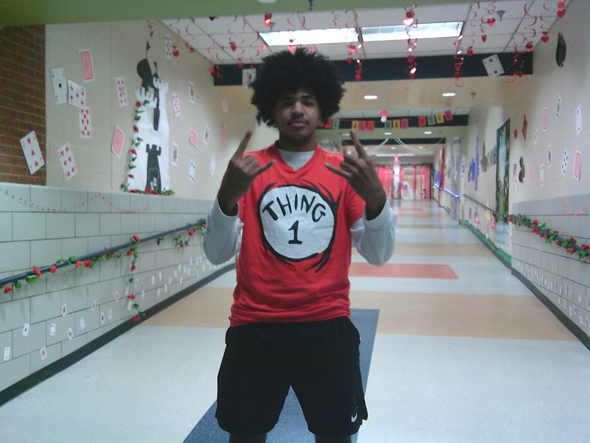 Senior Jaydon Hampton is showing his school spirit while being dressed as thing one. He is standing in the middle of the senior hallway which is matching the colors of his costume.