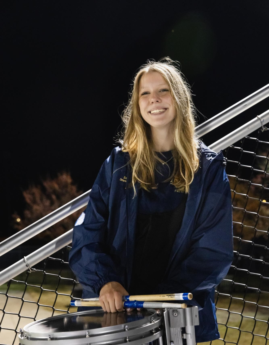 Playing in the stands at a football game, Zoe takes a break to smile for a picture.