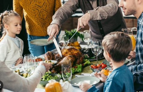 Father cutting open the golden brown turkey. The kids looking aimlessly at it.