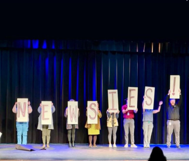 Standing in a straight line, teachers held individual boards to reveal one by one the new musical's name.