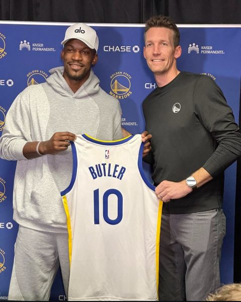 Jimmy Butler posing with the Warriors GM at his opening press conference them.